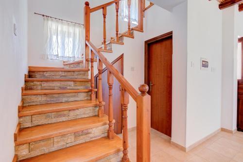 a staircase in a home with a wooden stair case at Sermar Villa in Episkopi Pafou