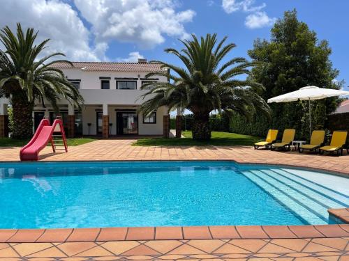 a swimming pool with a slide and chairs and a house at Green House in Ponta Delgada