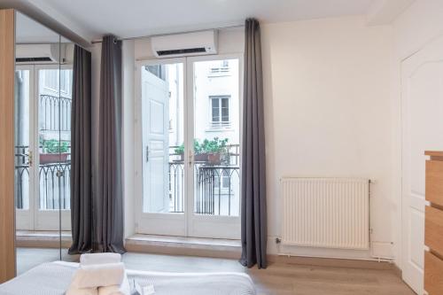une chambre avec un lit et une grande fenêtre dans l'établissement ART HOME - T2 au coeur de Lyon, à Lyon