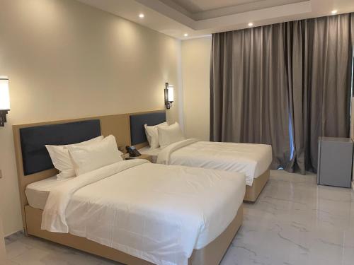 two beds in a hotel room with white sheets at Season Inn Hotel Apartment_Duqm in Duqm