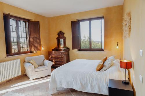a bedroom with a bed and a chair and windows at Agriturismo Qui Voglio in Monte Roberto