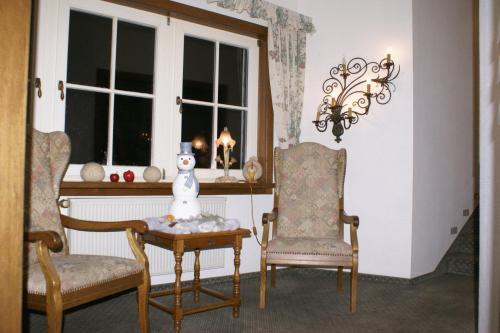 ein Zimmer mit zwei Stühlen und einem Tisch mit einem Schneemann darauf in der Unterkunft Haus Hennche in Siegen
