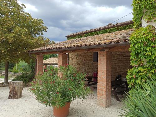 a brick pavilion with a table and a plant at Agriturismo Alla Vecchia Quercia in Pergola