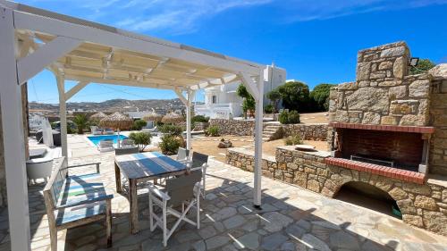 a patio with a stone fireplace and a table and chairs at Amperian Mykonos Suites & Villas in Mýkonos City