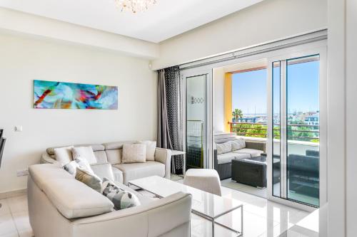 Una sala de estar con muebles blancos y una gran ventana. en Limassol Marina Nereids D22 by Ezoria Villas, en Limassol