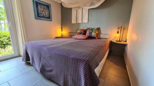 - une chambre avec un lit et une couette à rayures violettes dans l'établissement Sorbier, à Corbara