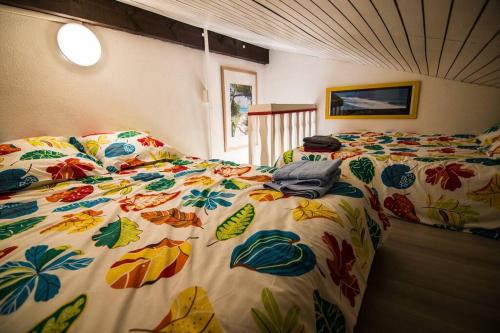 - une chambre avec 2 lits et une couette colorée dans l'établissement Appartement Seignosse le Penon/plage, à Seignosse