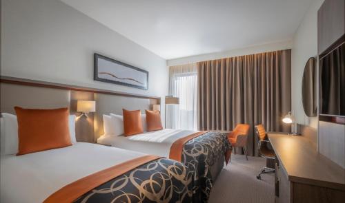 a hotel room with two beds and a desk at Clayton Hotel Manchester City Centre in Manchester