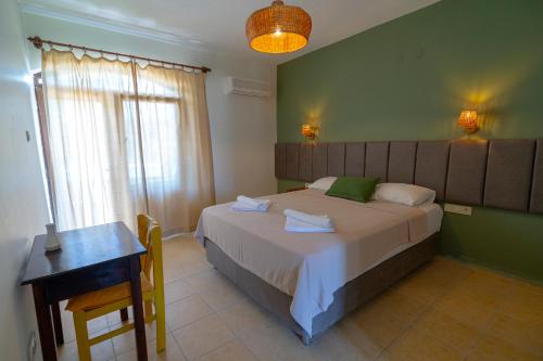 a bedroom with a bed and a table and a window at Xanthos Boutique Hotel Patara in Patara