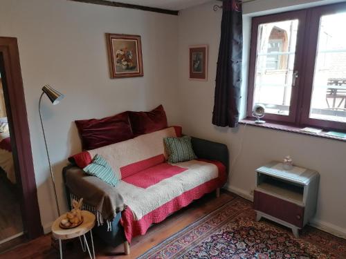 un canapé dans un salon avec une fenêtre dans l'établissement La Maison Vigneronne, à Riquewihr