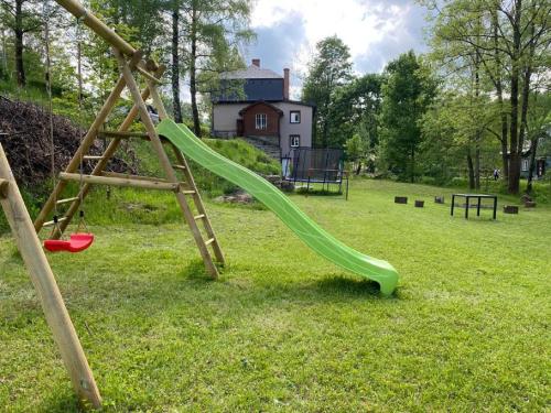 a playground with a green slide in a field at CHALUPA NAD POTOKEM in Zlaté Hory