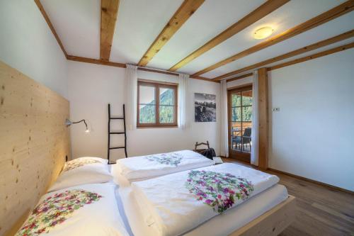 een slaapkamer met twee bedden met bloemen erop bij Fewo Bergpanorama Obertalerhof in San Martino