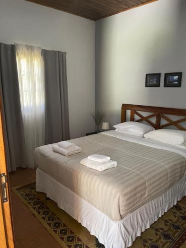 a bedroom with a large bed with two towels on it at Chalé Rio das Pedras in Santo Antônio do Pinhal