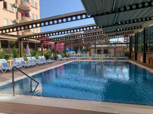 a large swimming pool with lounge chairs in a building at Club Sidar Apart Hotel in Alanya