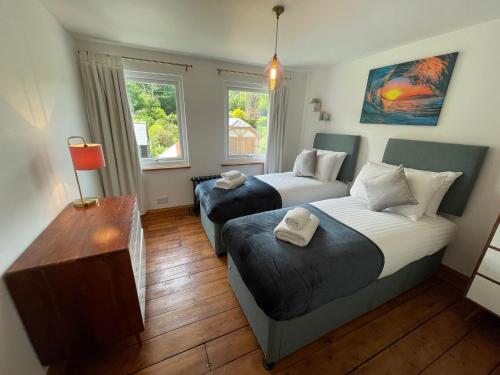 a bedroom with two beds and a table and two windows at Redlands Cottage Surrey Hills in Dorking