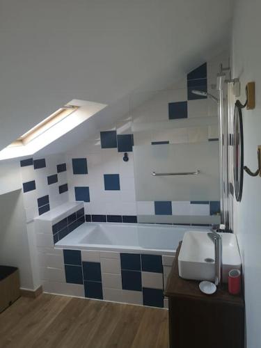 La salle de bains est revêtue de carrelage bleu et blanc. dans l'établissement Le passage des fées, à Couvains