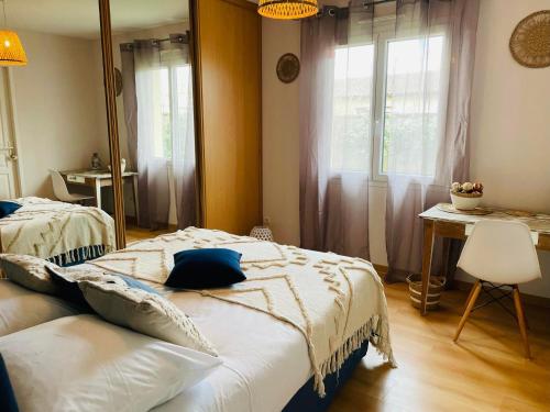 a bedroom with two beds and a table and window at Jolie maison LE TEICH bassin Park/wifi in Le Teich