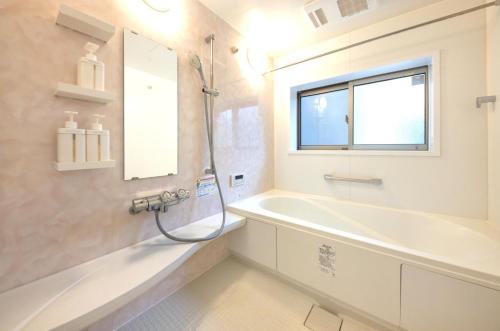 baño con bañera, lavabo y ventana en Holy Town en Tokio