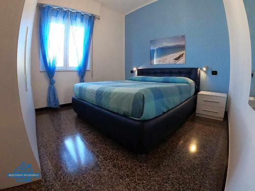 um quarto com uma cama com paredes azuis e uma janela em Apartament Arcobaleno a 500 metri dal mare em Albissola Marina