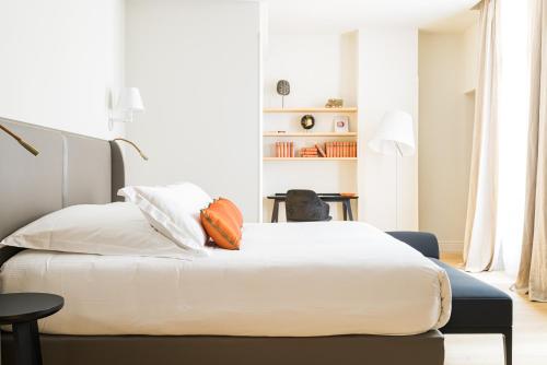 a bedroom with a bed with white sheets and orange pillows at Villas Foch Boutique Hotel & Spa Bordeaux in Bordeaux