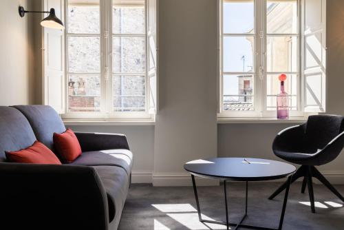 a living room with a couch and a table and windows at Villas Foch Boutique Hotel & Spa Bordeaux in Bordeaux