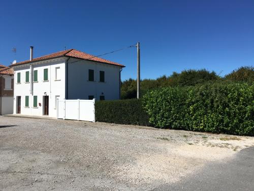 a white building with a red roof next to a hedge at Casa Sincielli in Caorle