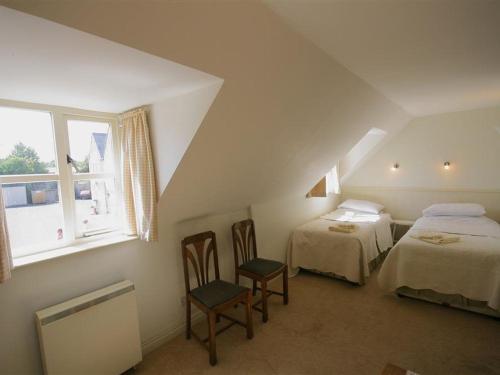 a attic room with two beds and a window at Noel Cottage in Chipping Campden