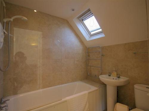 a bathroom with a bath tub and a sink at Noel Cottage in Chipping Campden