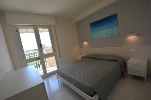 una camera con letto e porta di accesso a un balcone di Lignano Pineta with sea view a Lignano Sabbiadoro