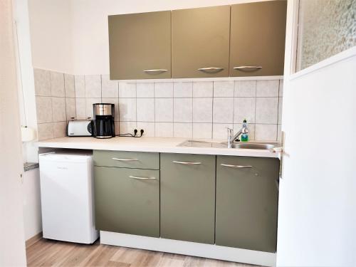 a kitchen with green cabinets and a sink at Bungalow Krzyzaniak in Lohsa