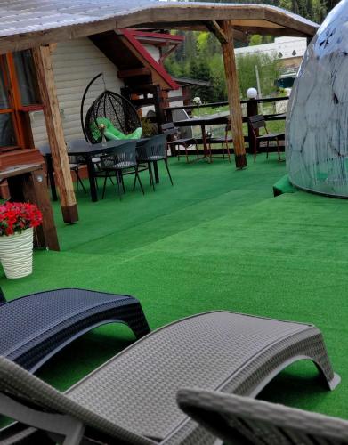 a patio with green grass and tables and chairs at Zdybanka in Bukovel