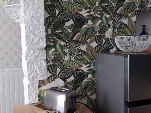 Il dispose d'une cuisine avec un réfrigérateur et un mur recouvert de papier peint. dans l'établissement Maison rénovée aux Sables d'Olonne, proche plage et port, 5 couchages, 3 Clévacances - FR-1-331-212, à Les Sables-dʼOlonne