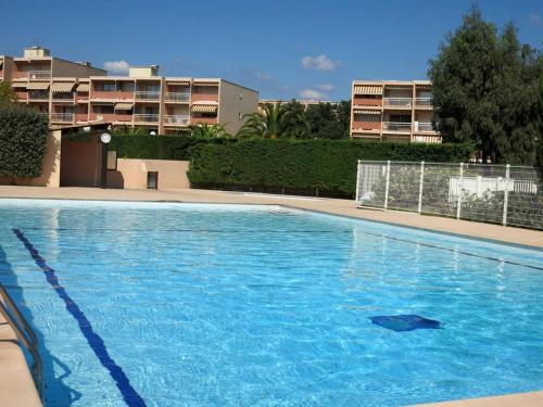 une grande piscine bleue avec des bâtiments en arrière-plan dans l'établissement Studio cabine climatisé avec piscine et parking à Bormes-les-Mimosas - FR-1-610-75, à Bormes-les-Mimosas