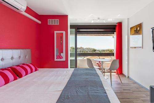 - une chambre rouge avec un grand lit et une table dans l'établissement Studio Vue mer panoramique, piscine Port Vénus village naturiste, au Cap d'Agde