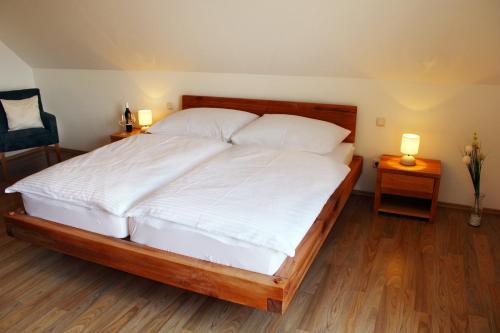 a bedroom with a large bed with white sheets and two lamps at Pension Lammerhof in Unterlamm