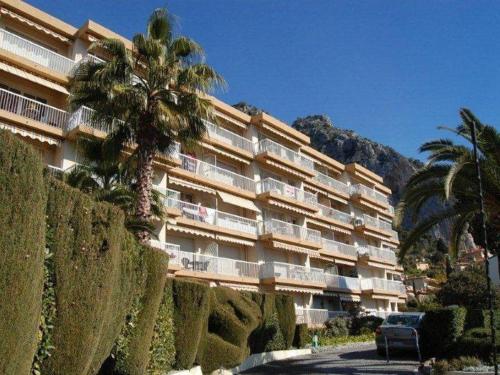 un grand bâtiment avec un palmier devant dans l'établissement Agréable 2 pièces rénové avec balcon exposé sud - FR-1-196-302, à Menton