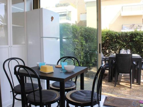 une table avec des chaises et un réfrigérateur sur la terrasse. dans l'établissement Studio en RDJ avec jardin, plage à 3m, clim et parking, Villeneuve-Loubet - FR-1-252A-74, à Villeneuve-Loubet
