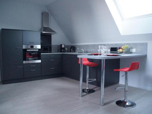 - une cuisine avec une table et des tabourets rouges dans l'établissement Studio de charme à la ferme près de Lille, 50m² avec cuisine équipée et parking sécurisé - FR-1-510-173, à Halluin