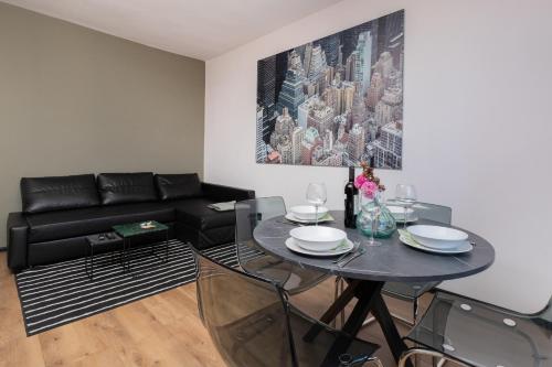 a living room with a table and a black couch at Port Gdynia Apartment by Renters in Gdynia