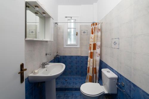 a blue and white bathroom with a toilet and a sink at Spertos Apartments in Órmos