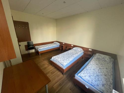 a room with three beds and a table in it at ANNA NOCLEGI in Raszyn