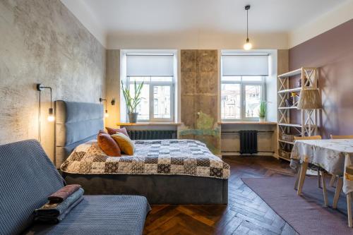 a bedroom with a bed and a table and two windows at Baltic Design Apartments with free Parking in Rīga