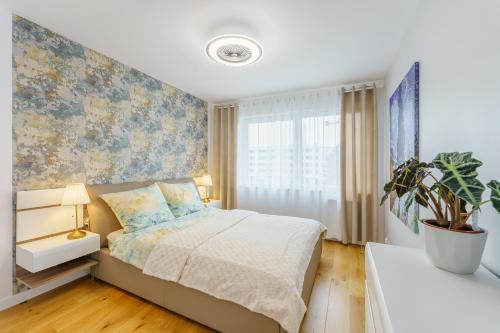 ein Schlafzimmer mit einem Bett und einer Topfpflanze in der Unterkunft Apartament Doro in Kołobrzeg