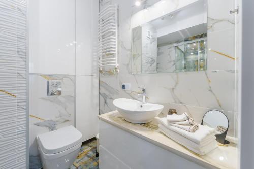 biała łazienka z umywalką i toaletą w obiekcie Apartament Doro w Kołobrzegu
