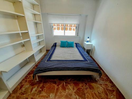 a bedroom with a bed with blue pillows and a window at Apartamento Murcia a tus pies in La Alberca
