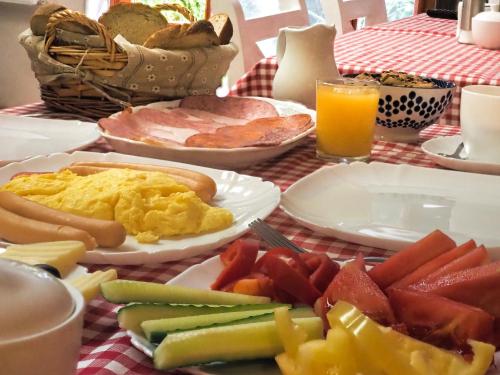 Una mesa cubierta con platos de desayuno y jugo de naranja. en Casa Camelia, en Sovata