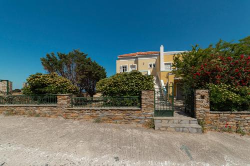 a house with a brick retaining wall and trees at Spertos Apartments in Órmos