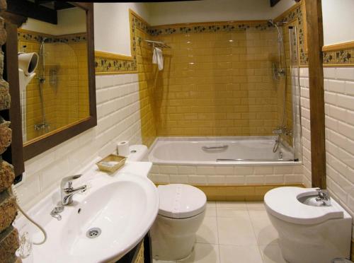 a bathroom with a sink and a toilet and a tub at Posada La Victoria in Miengo