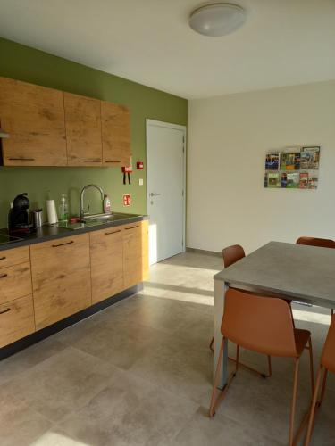 a kitchen with wooden cabinets and a table with chairs at Les jardins du Gauquier in Frasnes-lez-Buissenal