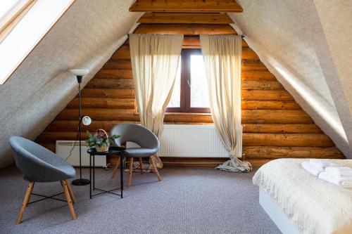 a bedroom with a bed and two chairs and a table at Hunter's Lodge in Padure